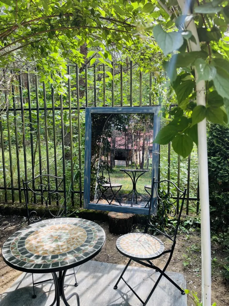 Close-up of a decorative mirror and mosaic table in the garden at Dworek Tryumf.