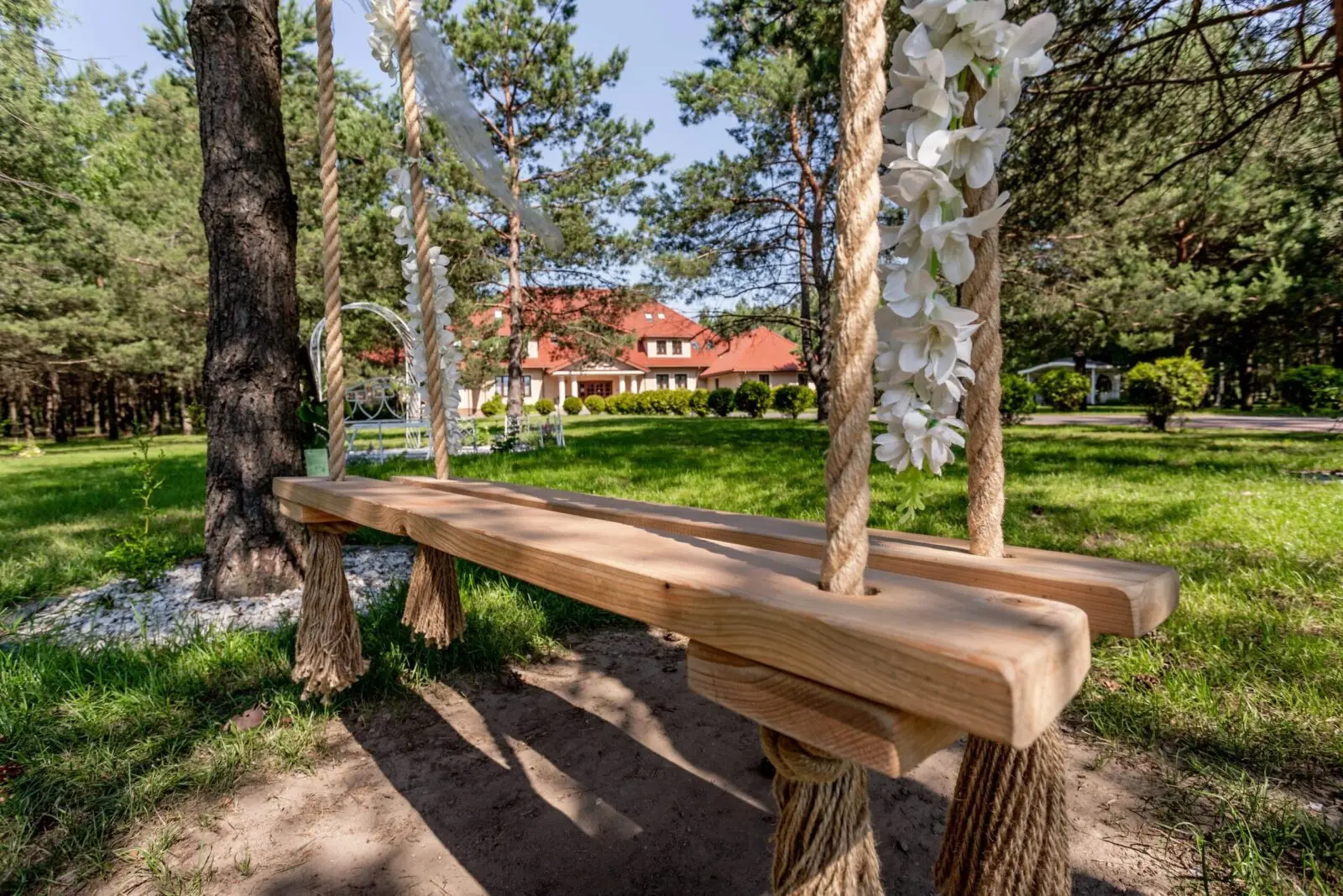 Wooden swing decorated with flowers in the garden at Dworek Tryumf.