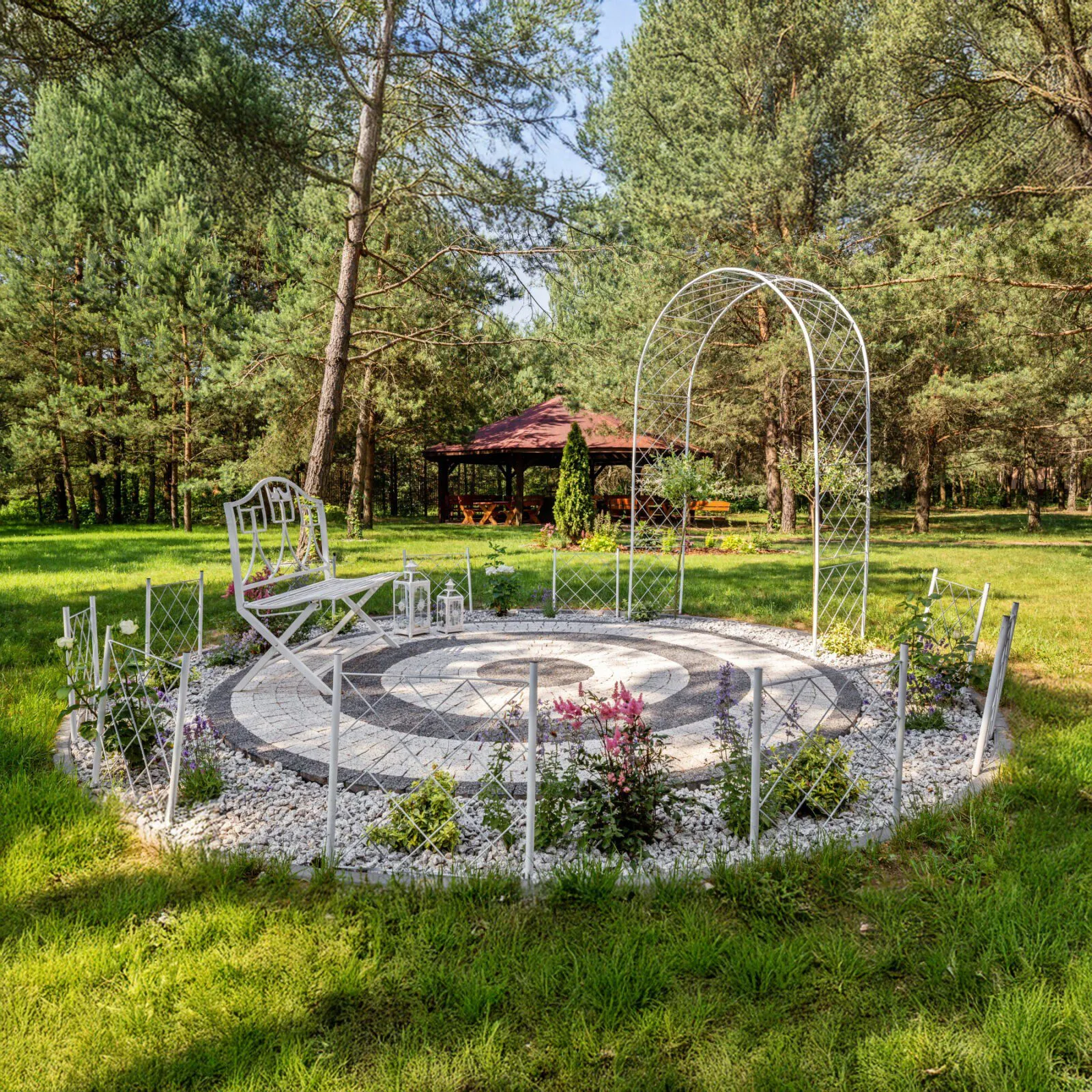 Charming garden nook with a white bench and arch at Dworek Tryumf.